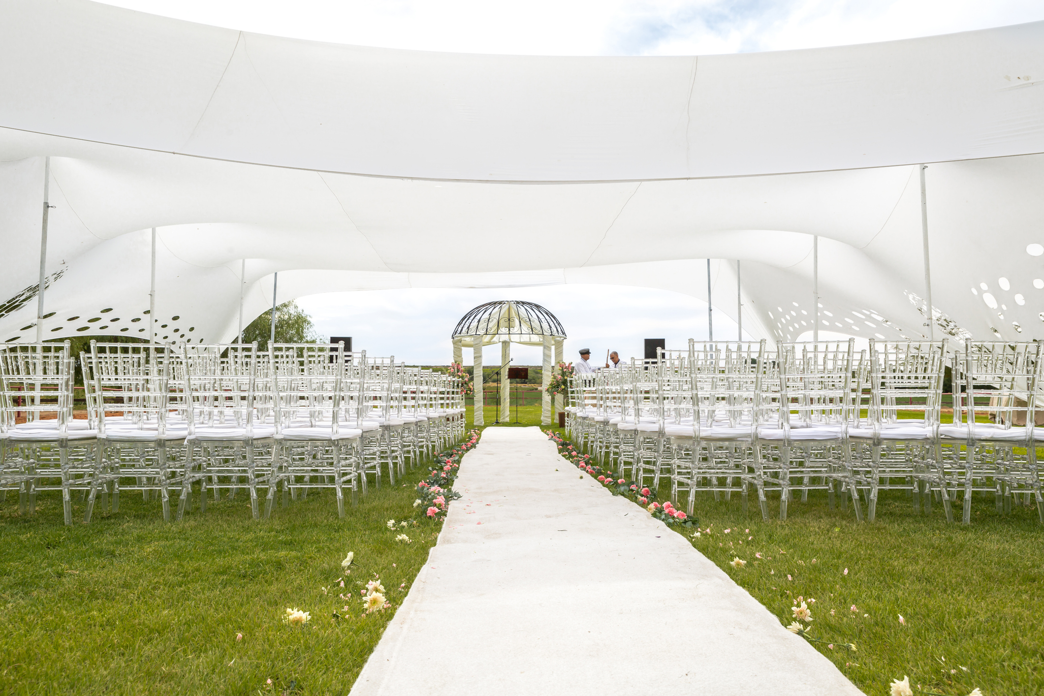 White wedding tent at outdoors venue with beautiful cloudscape and large green lawn
